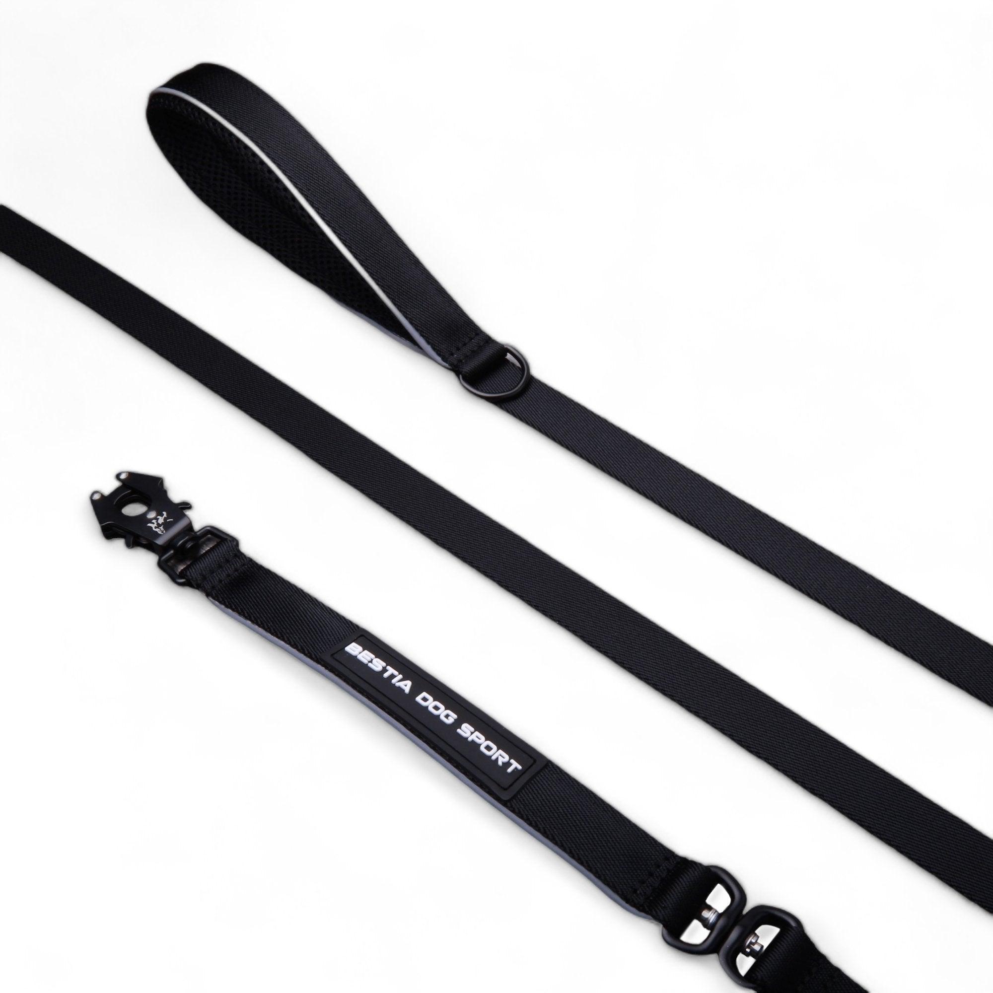 Eine schwarze BESTIA DOG SPORT GripPro Leine aus strapazierfähigem Nylon mit gepolstertem Griff, reflektierendem Besatz und Metallkarabiner, dazu ein passendes verstellbares Hundehalsband mit „IBIYAYA DOG SPORT“ Label.