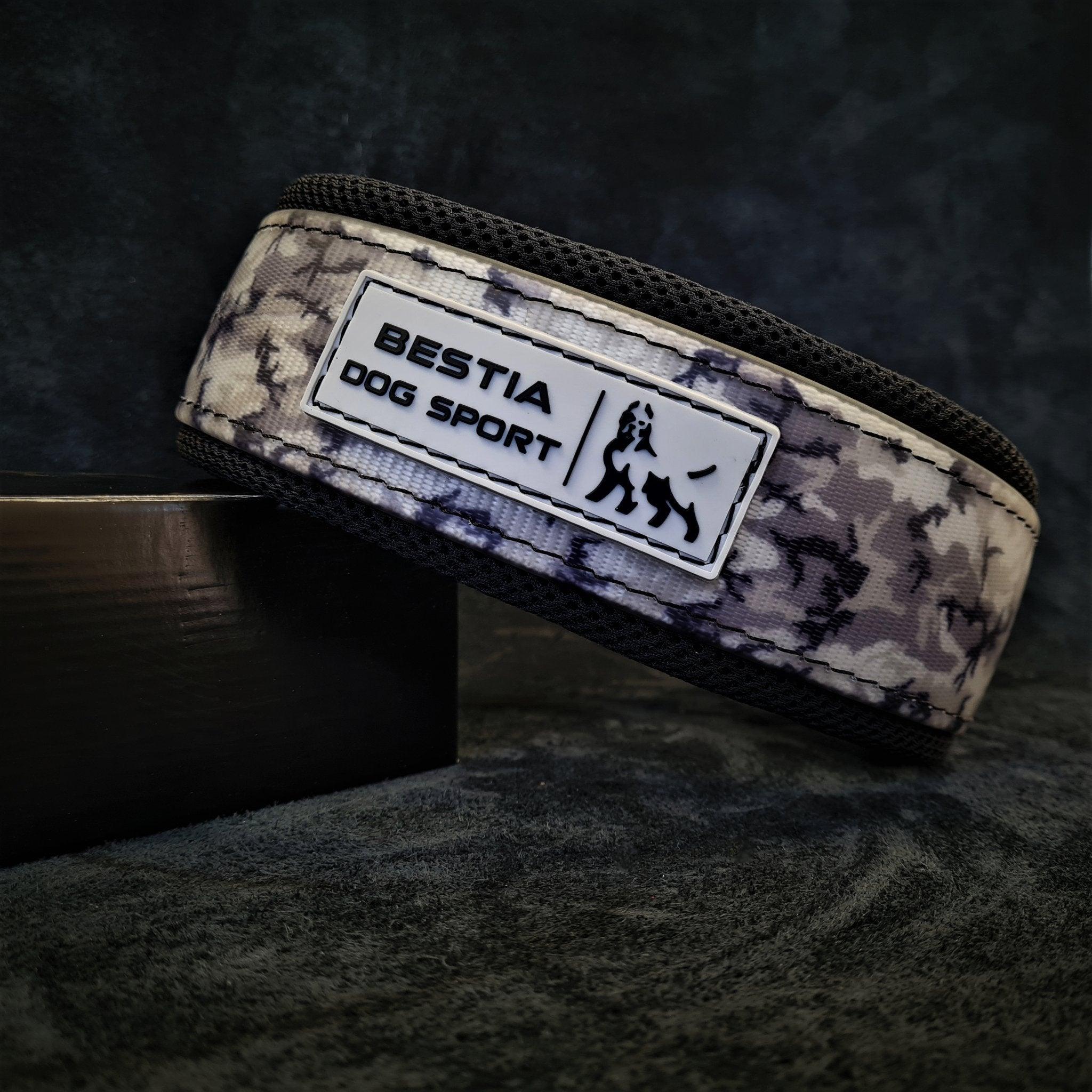 Eine Nahaufnahme des BESTIA DOG SPORT – BDS Halsbandes Grey Camo mit langlebigen Edelstahlbeschlägen und einem Aufnäher mit „BESTIA DOG SPORT“ und einem Hundebild.
