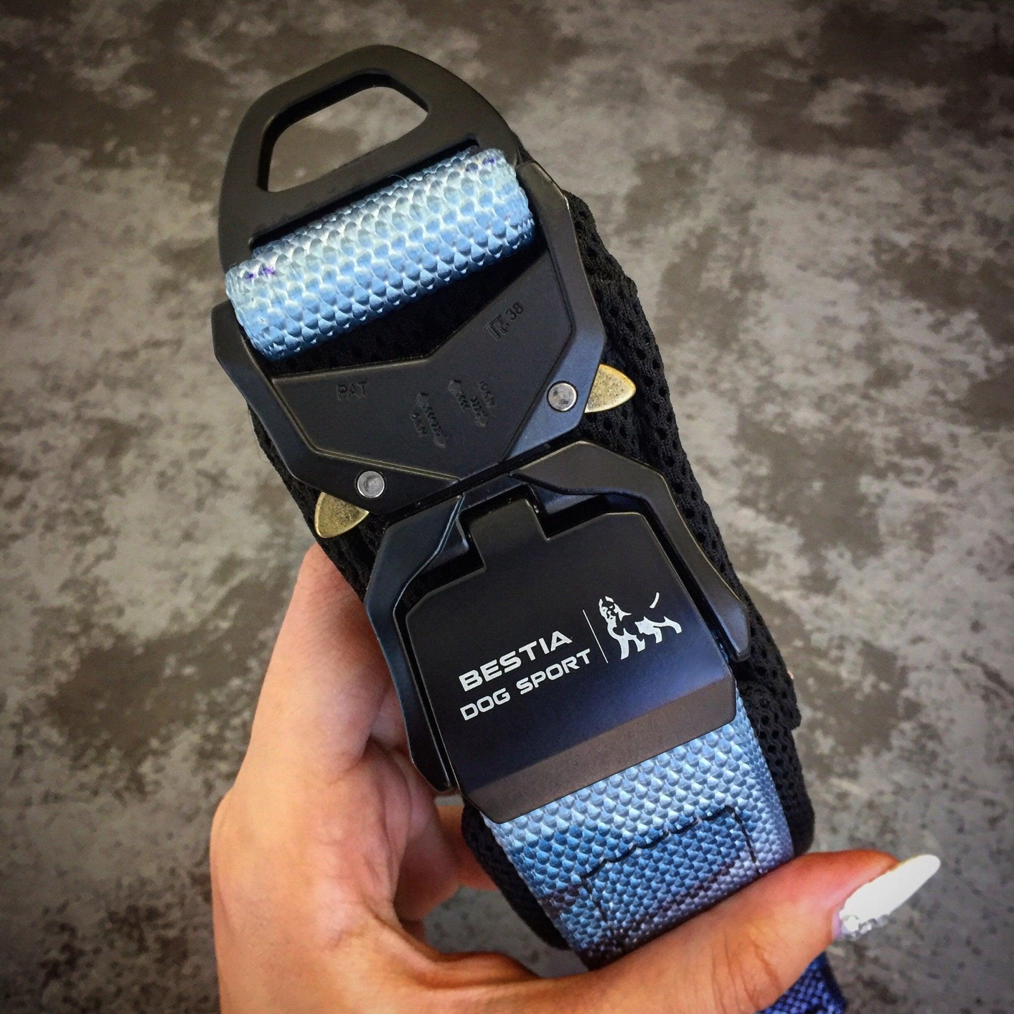 Eine Hand hält das BESTIA DOG SPORT – Schnellverschluss-Halsband Blue Camo mit Metallschnalle und strukturiertem blauem Camouflage-Stoff.