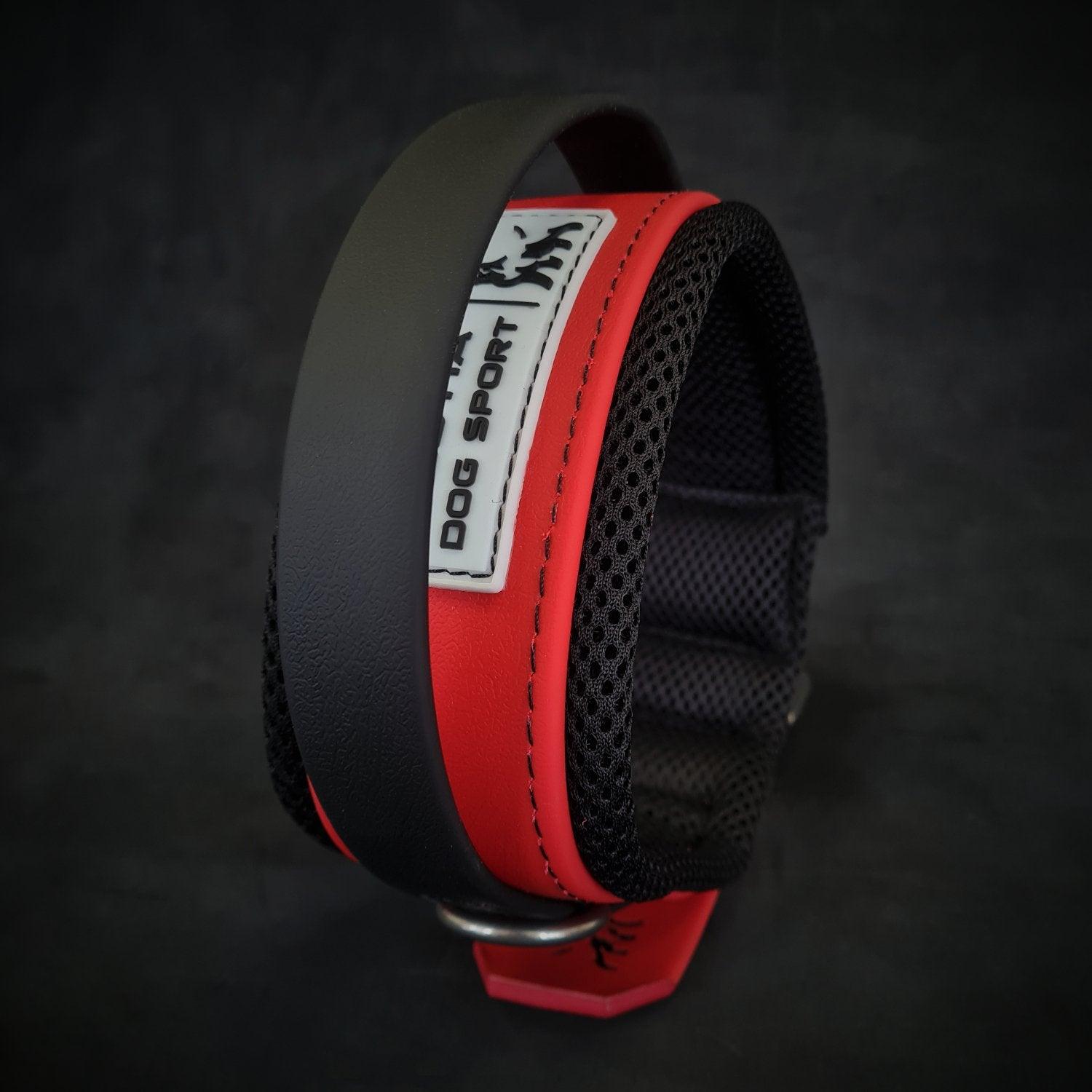 Eine Nahaufnahme des BESTIA DOG SPORT – BDS Handle Halsband Mattrot, einem robusten Hundehalsband von BESTIA DOG SPORT mit gepolstertem Futter, einem Metallring und einem weißen „DOG SPORT“-Etikett auf dunklem Hintergrund.