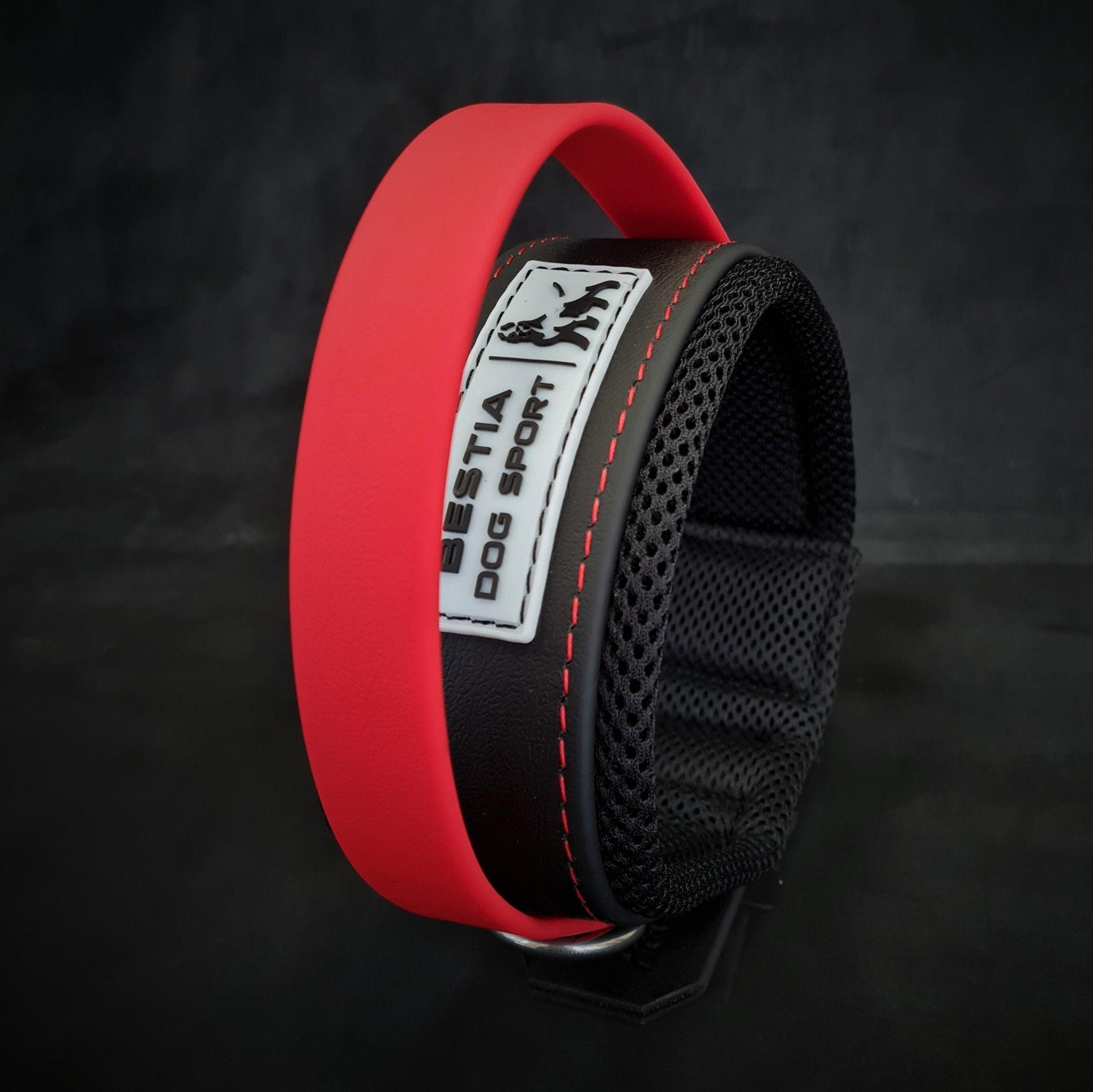Das BESTIA DOG SPORT – Handle Halsband mit rotem Griff ist ein schwarz-rotes Halsband für große Hunde mit einem weißen „BESTIA DOG SPORT“-Label, Netzfutter und Edelstahlbeschlägen, dargestellt vor einem dunklen Hintergrund.